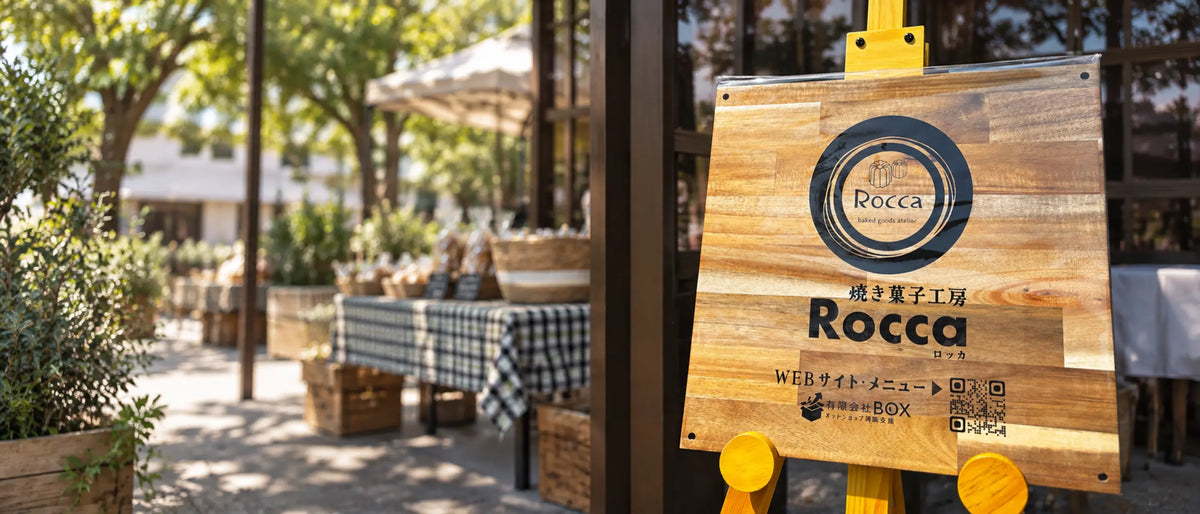 屋外マルシェに立つ焼き菓子工房Roccaの看板